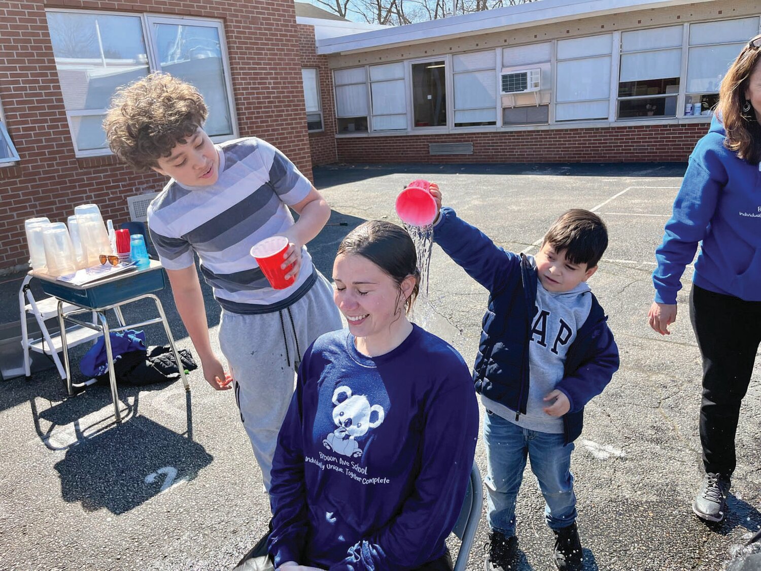 Fifth grader Angel Franco- Delgado with 2nd grader Gianluca Cambia pouring water over Ms. Sloan at the Brown Avenue's 2nd Annual Pay to Pour Event.